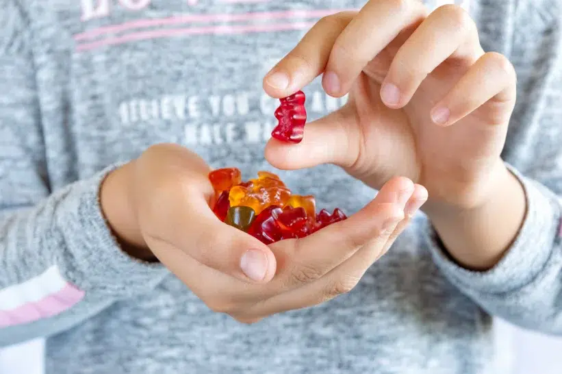 A man in sweatshirt holding different colored gummies